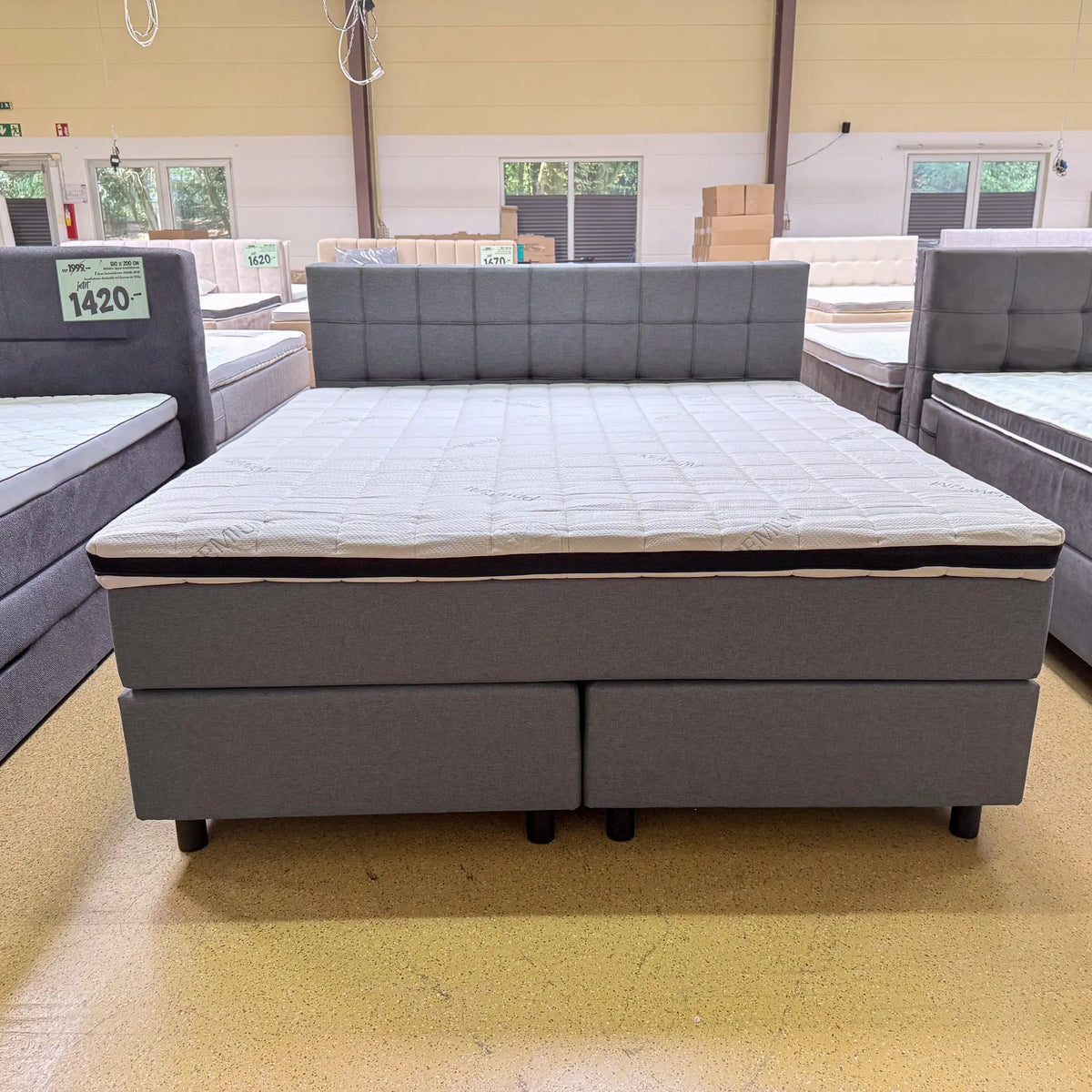Boxspringbett Finn mit fein gewebtem grauem Stoffbezug, gepolstertem Kopfteil und schwarzen Holzfüßen