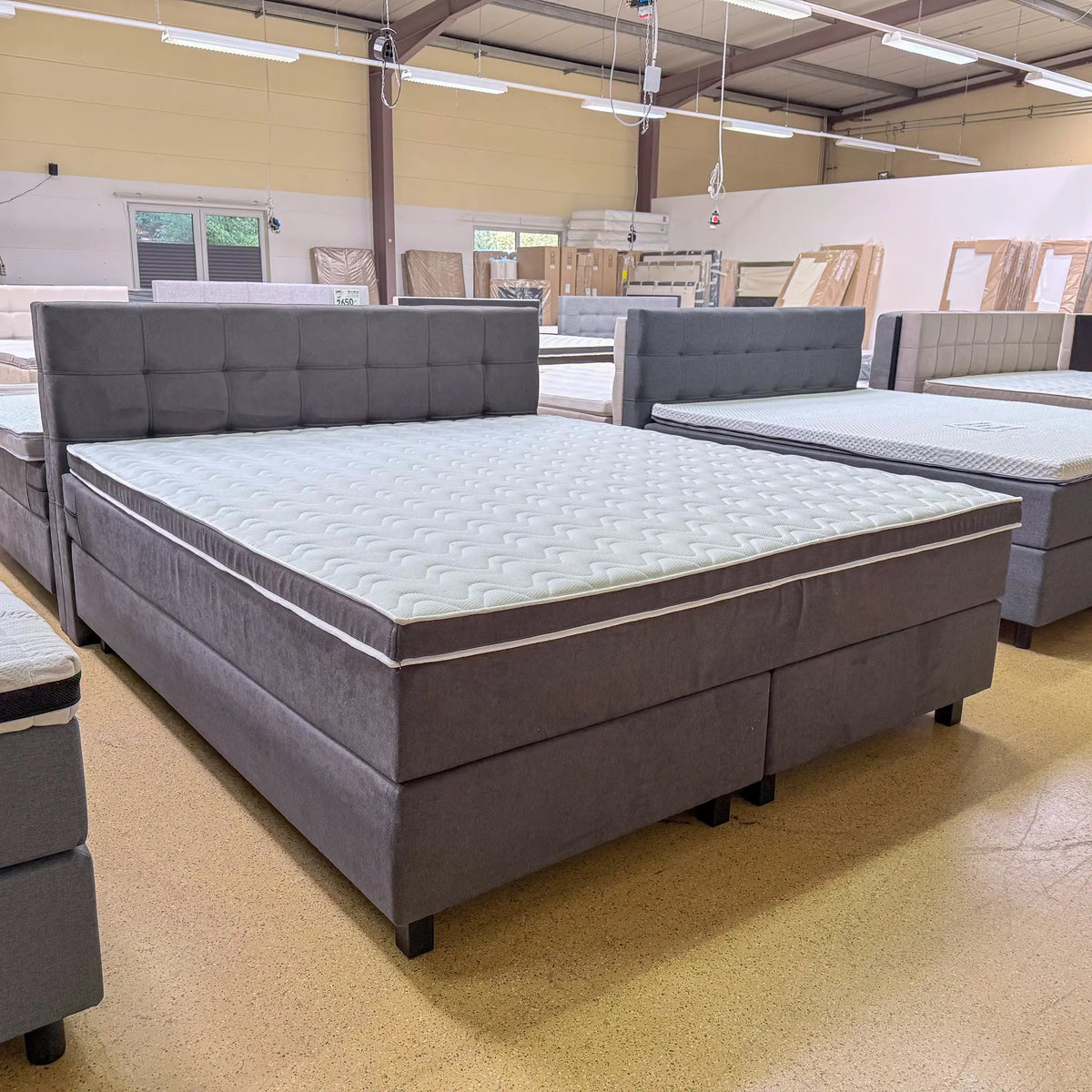 Boxspringbett Noah 200x220 in Anthrazit mit samtigem Stoffbezug, rechteckig gestepptem Kopfteil und Kaltschaumtopper, schräge Vorderansicht