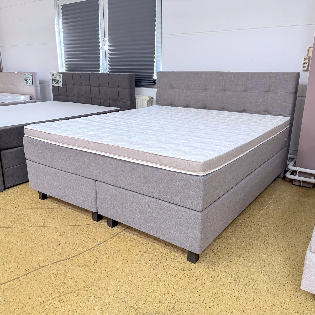 Boxspringbett Mats 180x200 in Taupe mit grob gewebtem Stoffbezug, gestepptem Kopfteil und Kaltschaumtopper, schräge Vorderansicht
