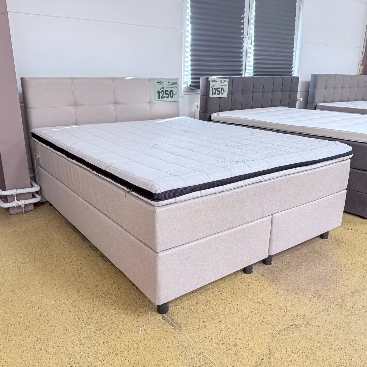 Boxspringbett Ben 160x200 in Beige mit fein gewebtem Stoffbezug, gestepptem Kopfteil und Visco-Komfortschaumtopper, schräge Vorderansicht